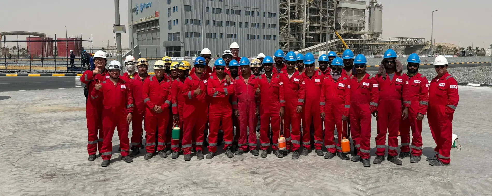 Das Team von XERVON Middle East steht in roten Schutzanzügen vor einem Gebäude. Header_AbuDhabi.jpg