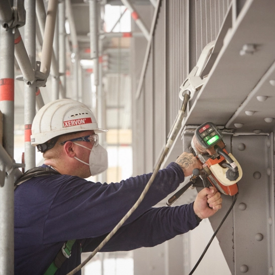 Arbeiter in Schutzausrüstung beim Schleifen eines Trägers