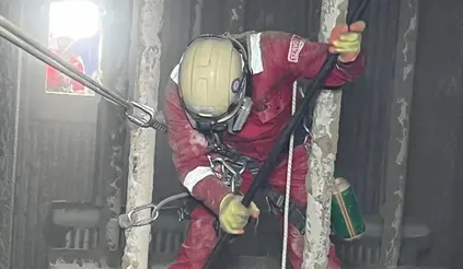 Mitarbeiter in rotem Schutzanzug reinigt den Kessel einer Müllverbrennungsanlage.